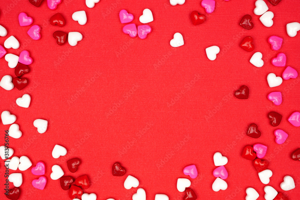 Valentines Day frame of candy hearts  over a red textured background. Above view with copy space.