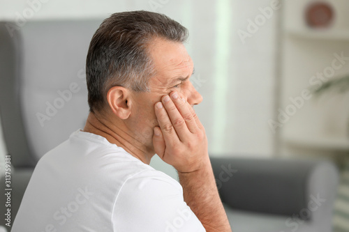 Mature man suffering from tooth pain at home