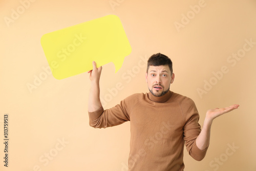 Confused man with blank speech bubble on color background