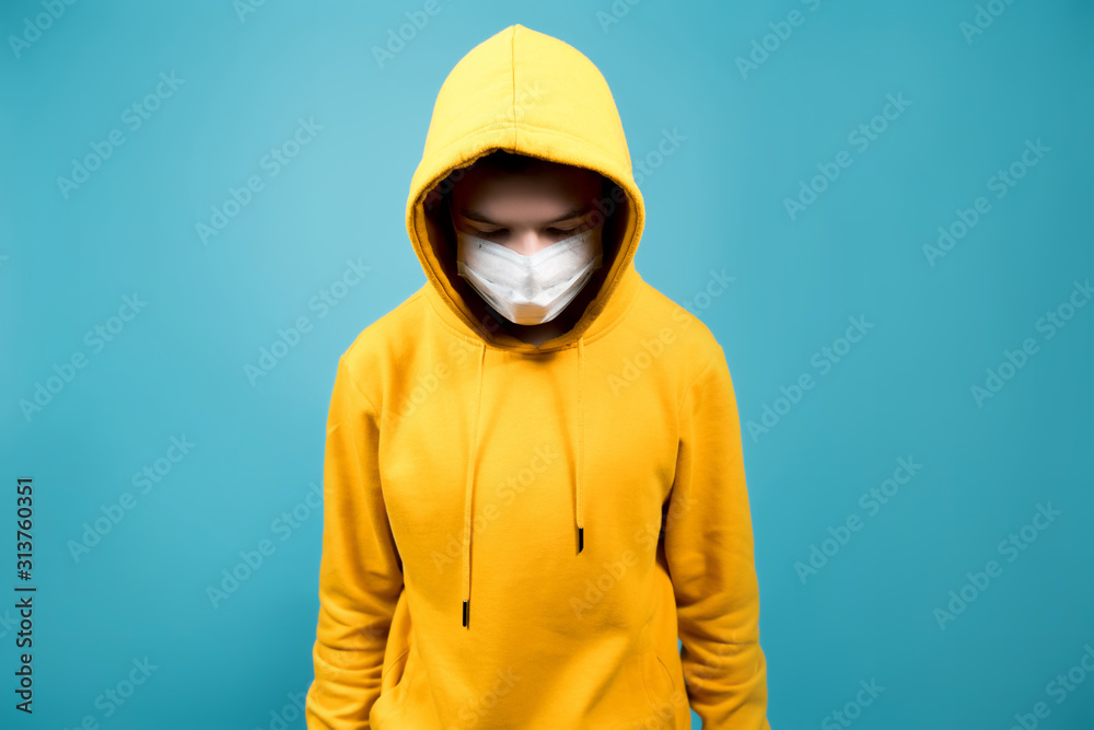 a young guy with a medical bandage on his face looks down. Blue background a young guy with a medical bandage on his face looks down. Blue background