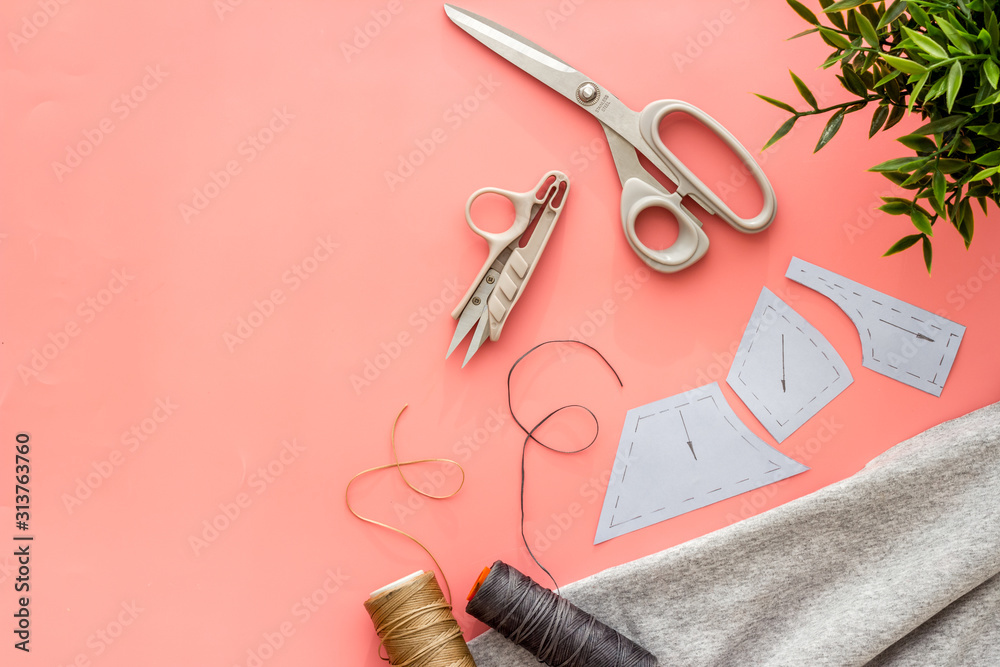 Sewing wokrshop. Textile, pattern, scissors, thread on pink background top-down copy space