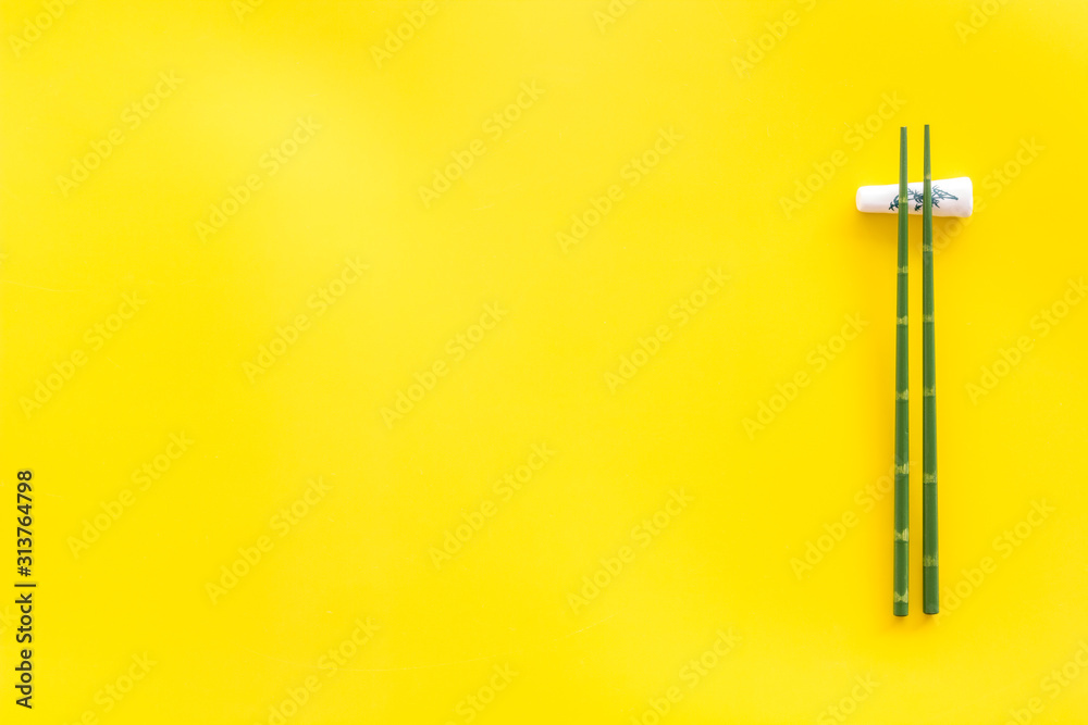 Chopsticks - green wooden utensil for sushi and rolls - on yellow background top-down copy space Chopsticks - green wooden utensil for sushi and rolls - on yellow background top-down copy space