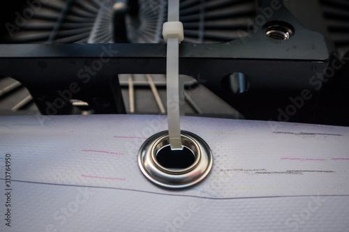Принти на полотні Metal ring or grommet on a vinyl banner, secured with a zip tie