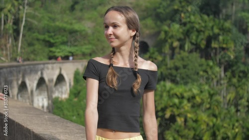 happy young woman sits on famous stone bridge and enjoys wild tropical nature slow motion closeup. Concept travel lifestyle photo