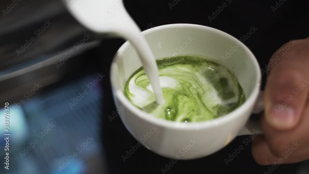 Barista pouring steamed milk over matcha powder. This was taken at a higher frame rate and has been converted to a slow motion video clip. Barista pouring steamed milk over matcha powder. This was taken at a higher frame rate and has been converted to a slow motion video clip.