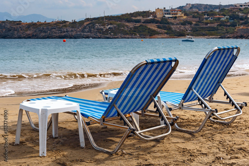 two sun loungers on the sandy beach of the Greek resort town of Agios Nikolaos © westermak15