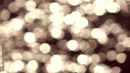 Amazing slow motion of blinking mica like specks on defocused ripple water surface with low sun reflection. Lyric beautiful gold toned background. Abstract pattern with excellent play of light.