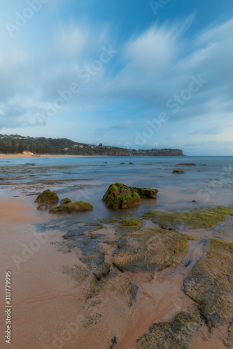 Mossy rock formation on the beach coastline.