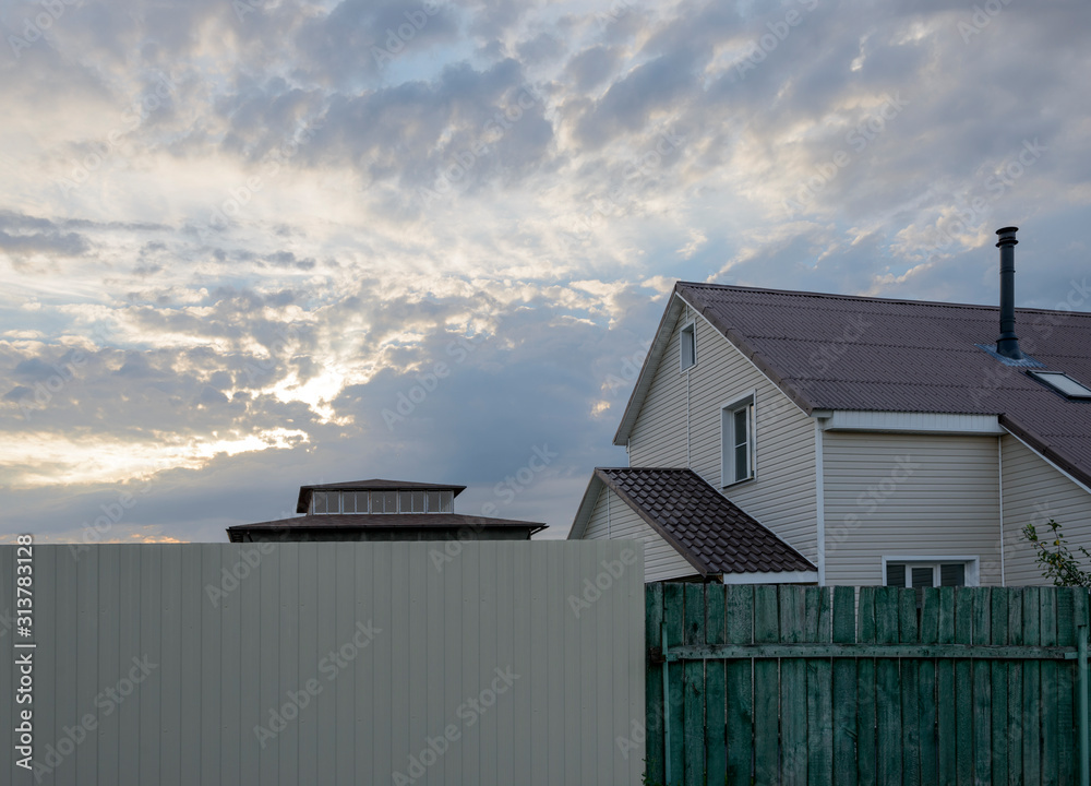 Cloudscape at summer sunset above the village fences.