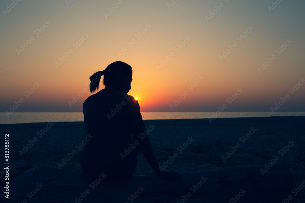 Beautiful woman sitting alone Lonely, disappointed and sad Heartbreak of life issues Style Silhouette during sunset.