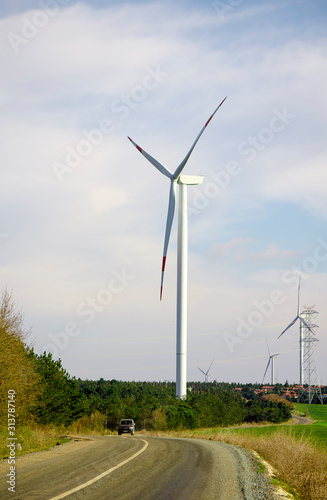 Wallpaper Mural Suburban landscape. Windmills on farm among fields. Sunny summer day. Blue sky with white clouds. Green forest along road. Alternative energy unity with nature concept. Copy space. Selective focus. Torontodigital.ca