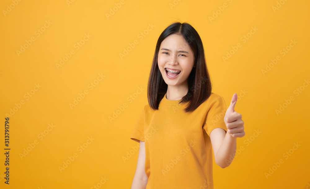 Smiling Asian woman and showing thumbs up or like on yellow background. Smiling Asian woman and showing thumbs up or like on yellow background.
