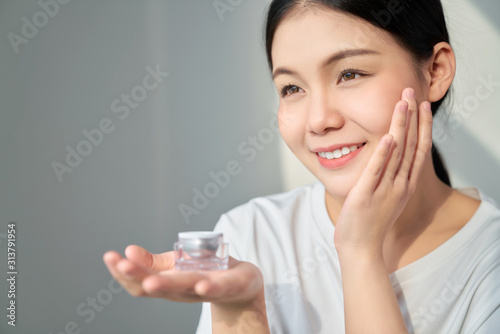 Smile Asian woman skin beauty and hand holding a product cream bottle for spa products and make up. The skin is smooth and beautiful.