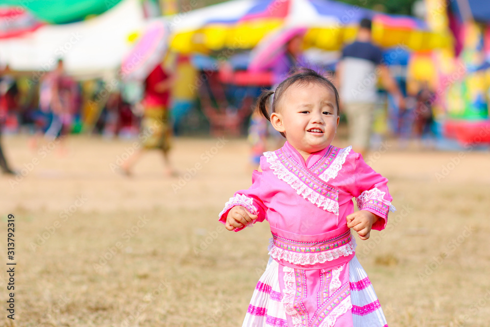 Naklejka premium Little child in Hmong costumes running on the ground on Hmong new year festival 2020