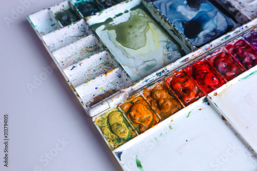 Painting palette box with dirty watercolor on table.