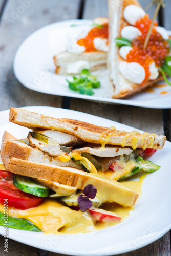 Classic breakfast, hot sandwiches with cheese, vegetables and chicken on a wooden table.