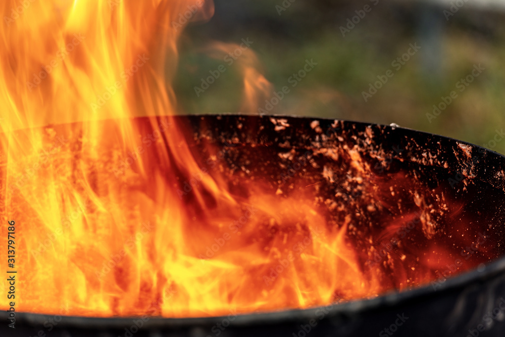 Close-up of flames in an old blackened metal bin - obrazy, fototapety, plakaty 