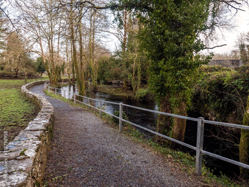 Empty path in a park by a river and stone fence.