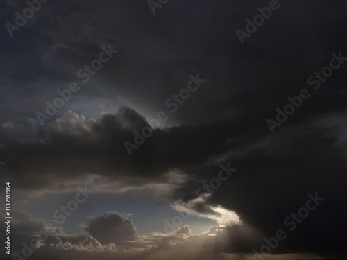 Dark clouds at sunset with rays of light shining through. Nature abstract background.