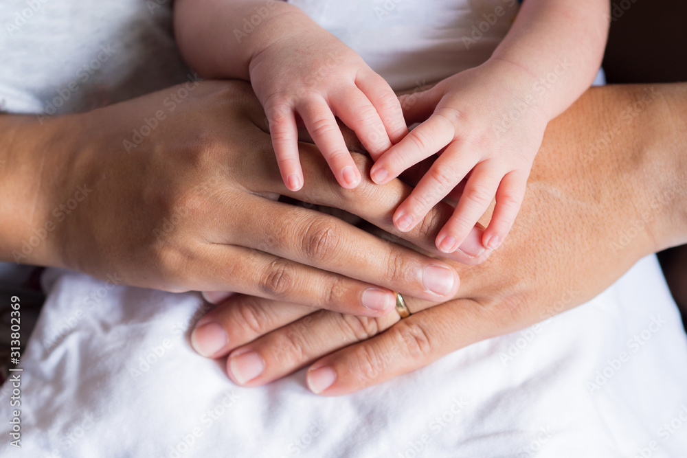 Close-up of newborn hands placed on mother and father hands on white cloth. Happiness parents. Love of family concept. Space for text Close-up of newborn hands placed on mother and father hands on white cloth. Happiness parents. Love of family concept. Space for text