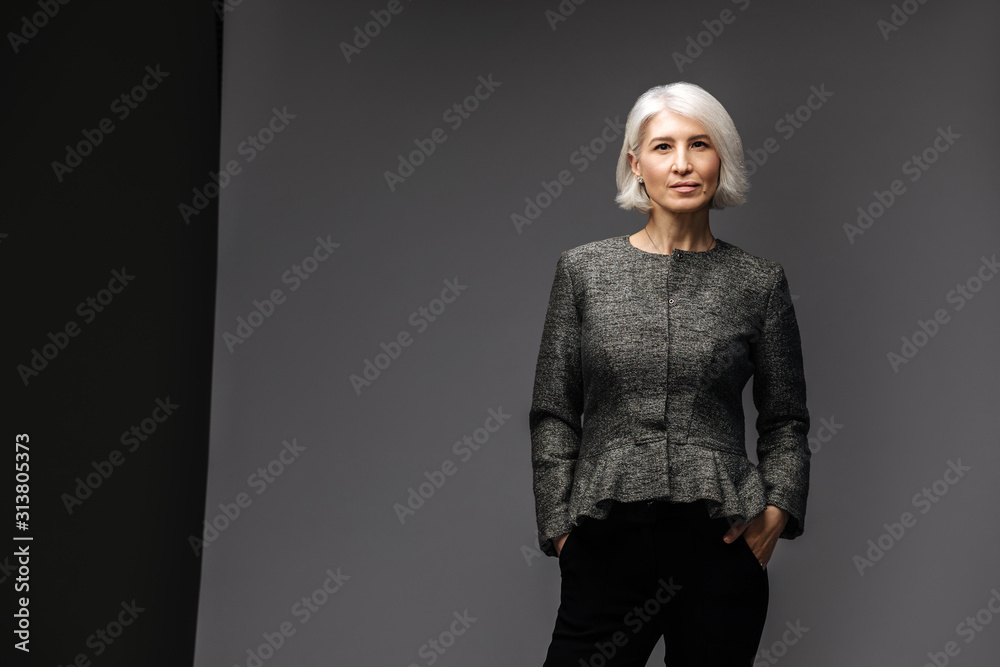 Fototapeta premium Business senior woman in blazer on grey background