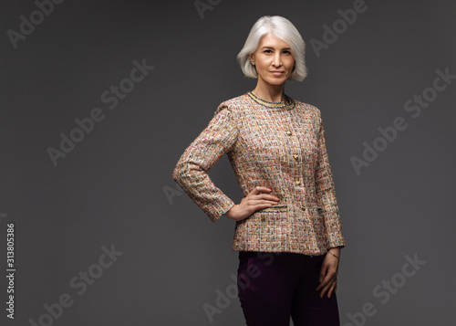 Business senior woman in blazer on grey background