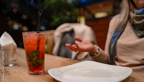 A woman drinks an alcoholic cocktail in a cafe. Close-up of a woman drinking a red cocktail in a cafe. Drinks, people and lifestyle concept-close