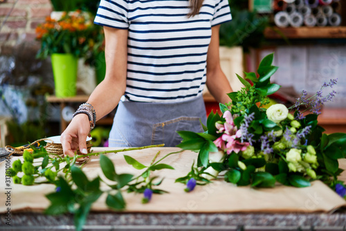 Female florist preparing big bouquet of flowers at the counter