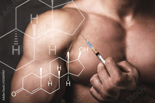 Muscular man with a syringe in his hand and testosterone formula. photo