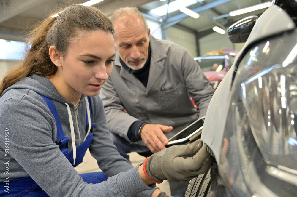 Apprentice with instructor working on vehicle - obrazy, fototapety, plakaty 