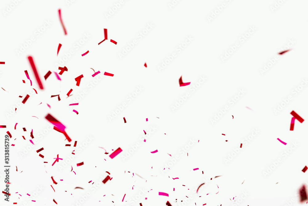 Confetti explodes on a white background. Festive salute of shiny red paper. Background decoration for a holiday, party, birthday or anniversary. Pieces and scraps of red ribbon