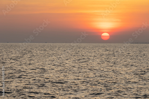 The red sun over the evening sea near the industrial area by the sea