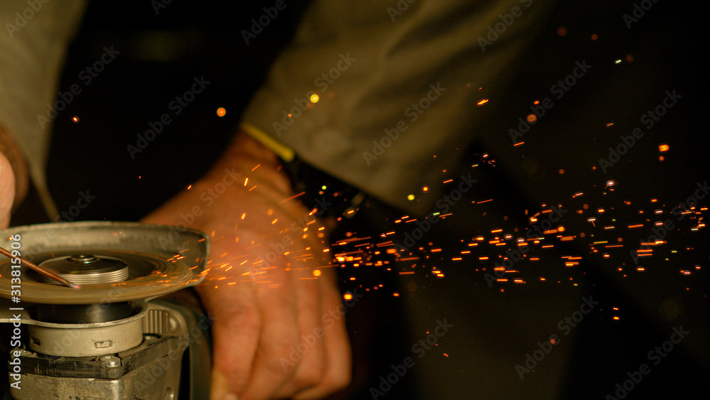 CLOSE UP, DOF: Circular angle grinder spins and grinds a small metal stick.