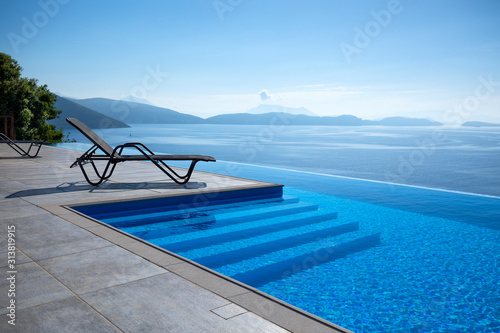 Infinity pool with chairs  With a view of the sea  photo
