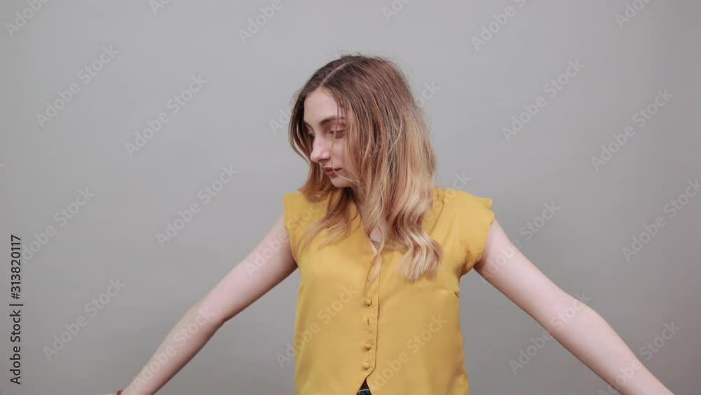 Disappointed woman spreads hand, looking at camera wearing fashion yellow shirt isolated on white background in studio. People sincere emotions, lifestyle concept.