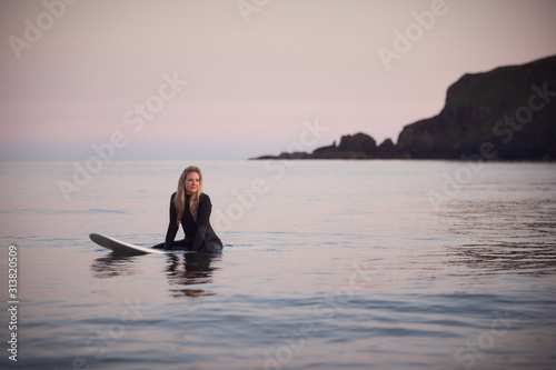 Woman Wearing Wetsuit Sitting And Floating On Surfboard On Calm  Sea © Monkey Business