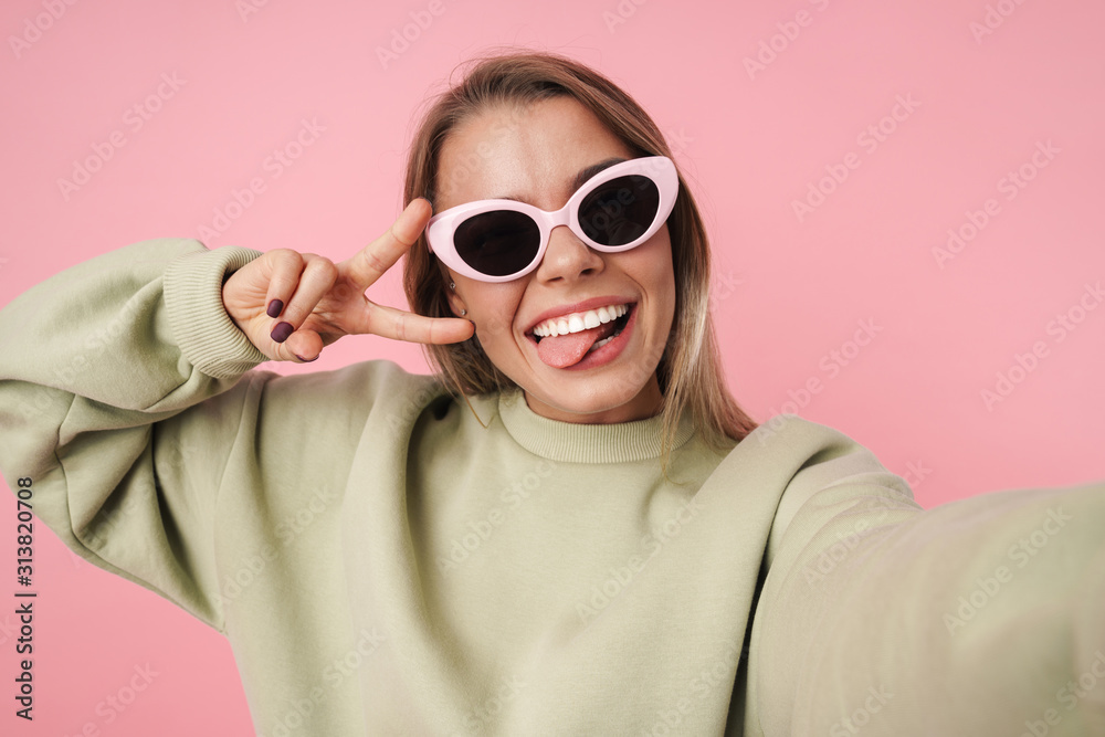 Portrait of smiling woman gesturing peace sign and taking selfie Portrait of smiling woman gesturing peace sign and taking selfie