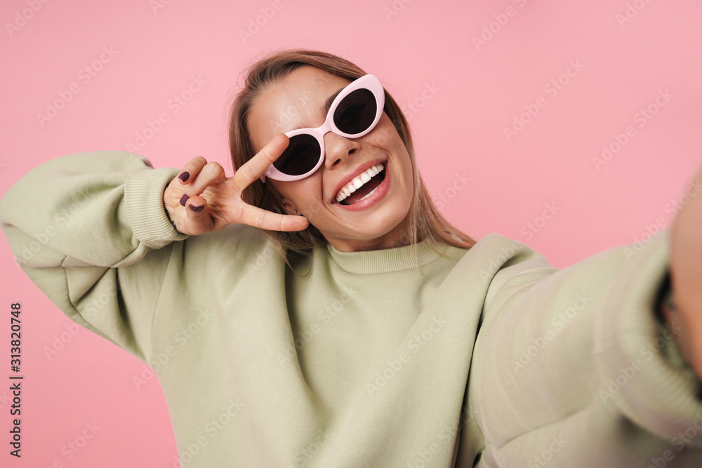 Portrait of smiling woman gesturing peace sign and taking selfie Portrait of smiling woman gesturing peace sign and taking selfie