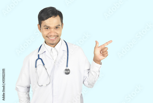 Young doctor smiling with stethoscope and pointing up with one finger got a good idea on blue pastel background.
