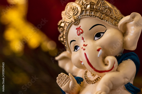 macro close up of beautiful ganesha statue in blessing pose against blurred red and golden background. religion and hindu concept.