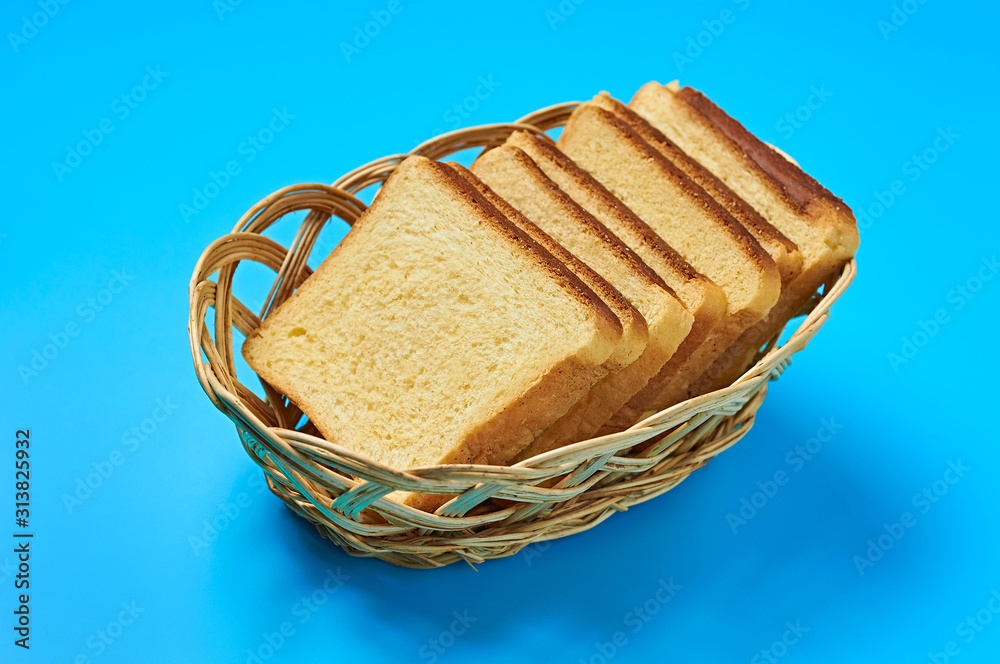 Wooden basket full of square pieces of yellow vanilla bread for toast lies  on blue table on kitchen. Close-up Stock Photo | Adobe Stock