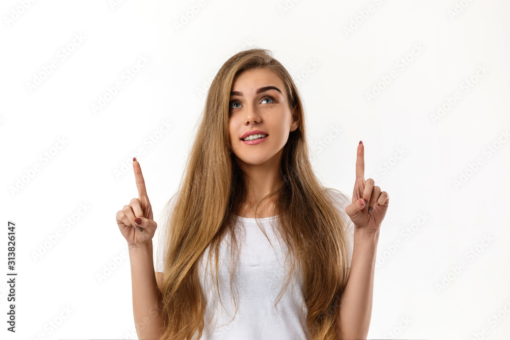 smiling young woman pointing up on white background. smiling young woman pointing up on white background.