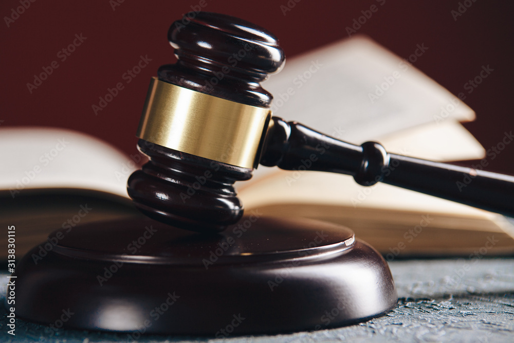 Law concept - Open law book with a wooden judges gavel on table in a courtroom or law enforcement office on black background. Law concept - Open law book with a wooden judges gavel on table in a courtroom or law enforcement office on black background.