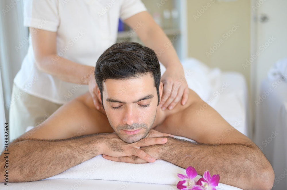 The young man closed his eyes and massage the face and head at the spa. The young man closed his eyes and massage the face and head at the spa.