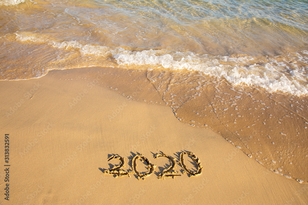 Fototapeta premium 2020 summer beach holiday season written on golden sand washed away wave - new season lettering on sand - numbers 2020 year travel vacation sandy wavy water yellow blue azure aquamarine turquoise