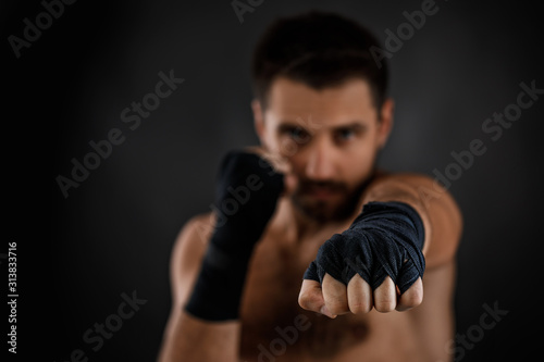 boxer man with bandage on hands training before fight and showing the different movements on black background. focus on hand © producer