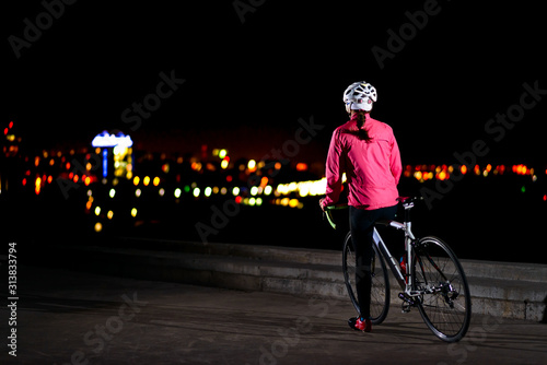 Woman Cyclist Resting with Road Bike and Looking at Night City Lights. Healthy Lifestyle and Urban Sport Concept