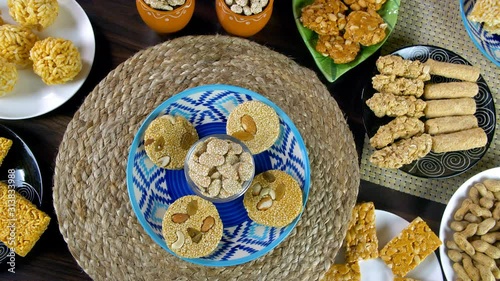 Beautifully plated homemade sweets consumed during Lohri festival - winter season. Top view shot of dry fruit gajaks with a bowl of rewri rotating on a turntable surrounded by different Lohri items... photo