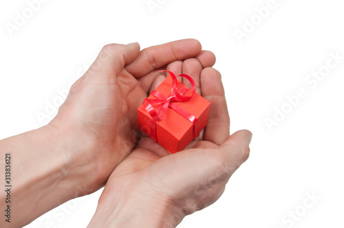 the palms of the right and left hands together hold a red gift box tied with a red shiny ribbon on a white background top view
