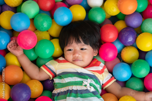 Happy Asian girl (one and half years olds) playing little colorful balls in pool ball. The concept of playing is the best learning for children.